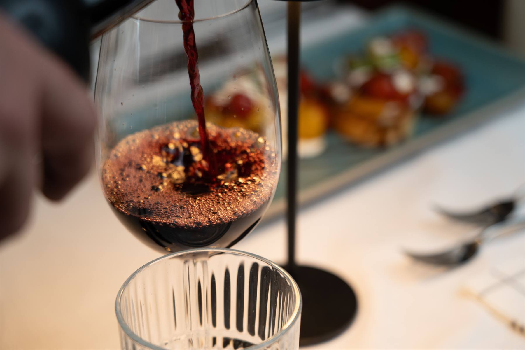Rotwein wird am Tisch eingeschenkt