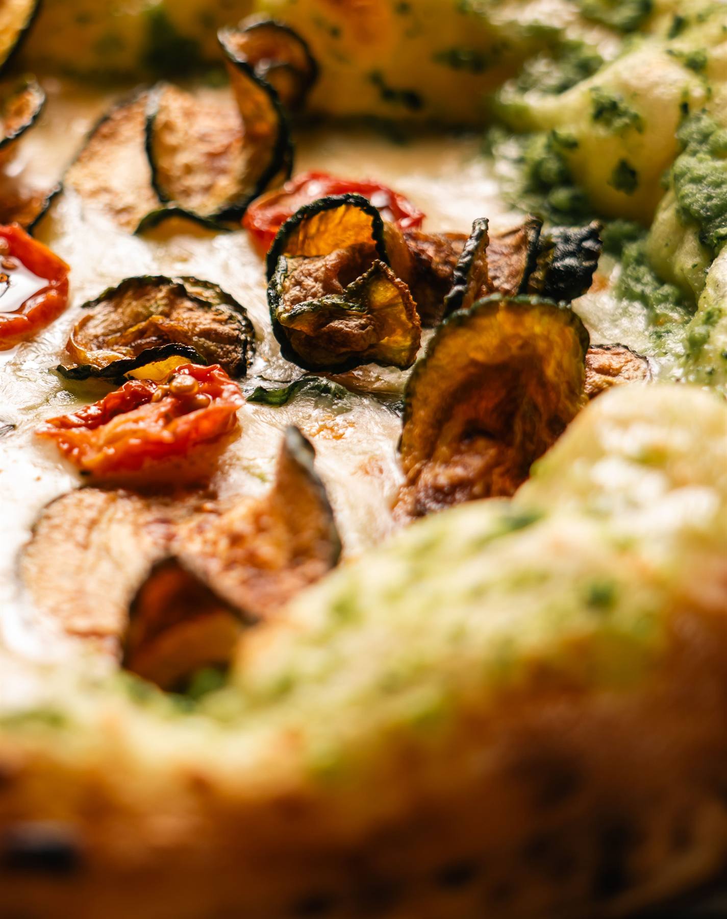 Nahaufnahme der Pizza mit Zucchettichips und Tomaten